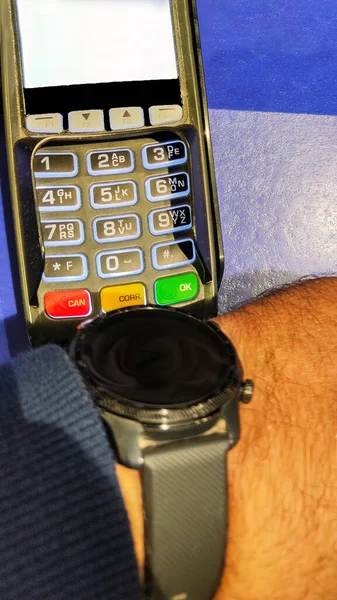 person using a smart watch to pay the bill by portable banking device or point-of-sale terminal with selective focus