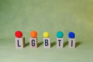 LBGTI kelimesi sarı arkaplan üzerine ahşap harfler ve lbgti bayrağının renginde toplar kullanılarak kopyalama alanı ile ilgili bir kavramı göstermek için oluşturuldu..