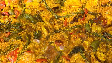 Geleneksel Valensiyalı paella. Pilav, sebze, et ve taze pişirilmiş biberiye dalları.