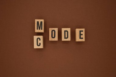 Kahverengi arkaplan, programlama ve tarz kavramı üzerinde kod ve mod kelimelerini oluşturan tahta bloklar.