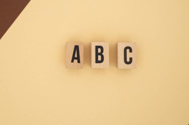 Açık bej zemin üzerinde A B C harfli tahta bloklar düzenli düzende