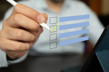 Dijital ekran ile etkileşime girerken beyaz bir stil tutan adam, etkileşimli grafik listesindeki bir kutuyu işaretliyor. Sahne, organizasyon, görev yönetimi, verimli planlama ve modern teknolojinin iş başında kullanımı kavramlarını yansıtıyor. 