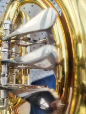 Parlak pirinç tuba valfleri, bir müzisyenin enstrüman çalması gibi yakından görülür.