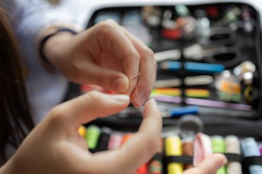 Dikiş ipliği iğnesine yakın çekim, arka planda renkli dikiş setiyle dikiş projesine hazırlanma