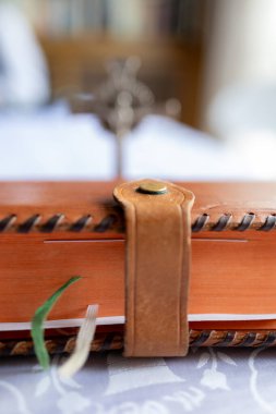 Portakal rengi deri ciltli bir günlük ya da arka planda masa üzerinde duran gümüş haçlı bir günlük.