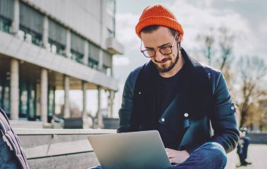 Beyaz tenli erkek blogcu, tanıtım alanında boş zamanlarında web siteleri için içerik metni oluşturmak için yeni uygulama yüklemek için dizüstü bilgisayarda yazılım güncelliyor.