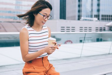 Asyalı stil sahibi bir kadın elinde kahve bardaklarıyla Hong Kong 'un caddesinde sörf yapmaya gidiyor.