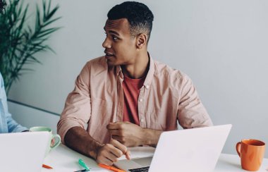 Çok kültürlü erkek meslektaşlar dizüstü bilgisayarlarda işbirliği yapmak için dizüstü bilgisayar başvurusu için veritabanı bilgilerini başlatmaktan bahsediyorlar.