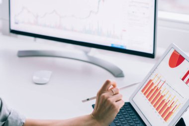 Modern ofisin penceresinin yanında bilgisayar ve tabletle çalışan çağdaş, zeki iş kadınının yan görünüşü