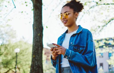 Spring City sokaklarında yürürken cep telefonuyla GPS 'i takip eden mutlu milenyum kadını, seyahat gezisi hakkında içerik yayını yapan pozitif stil hippi kız,