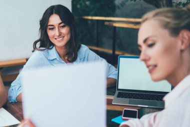 Bulanık bir bayan, terasta masada otururken ve serbest proje üzerinde çalışırken meslektaşlarına bilgilerle birlikte gülümsüyor ve kağıtları gösteriyor.