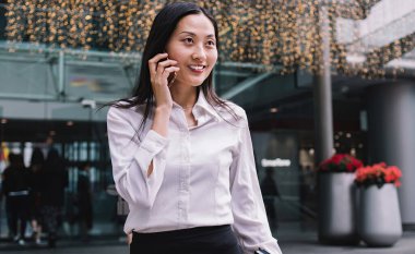 Ofis binasının önünde merdivenlerden inerken organizatörüyle konuşan oldukça mutlu, resmi giyinmiş, Asyalı bir kadın.