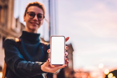 Bulanık arka planda, seyahat gezisinde 4G kablosuz bağlantıya sahip modern akıllı telefon cihazını gösteren bin yıllık kadın turist, çevrimiçi web sitesi için görüntüleme