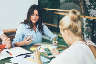 Proje hakkında brifing sırasında telefonlarda sörf yapan ve terastaki belgelerle masada buluşurken fikir arayan genç işçilerle ciddi etkileşimler.