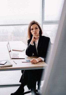 Ciddi kadın meslektaşlar birlikte masaya oturma fikrine odaklanmış, resmi olarak giyinmiş kadınlar ofiste üretken çalışma süreçleri üzerinde kafa patlatıyorlar.