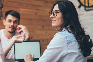 Gündelik genç iş kadınları aktif olarak iletişim kuruyor ve birbirlerine bakıyorlardı. Akıllı telefondan konuşan bir erkeğin karşısında dizüstü bilgisayarın önünde.