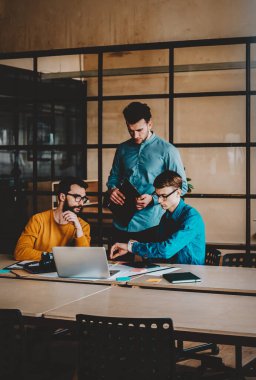 Modern ofis için modern dizüstü bilgisayarı kullanarak sunum oluşturma konusunda işbirliği yapan genç profesyonellerden oluşan bir ekip. İş bilginiz için tanıtım alanı