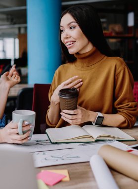 Kafkas kadın çalışanlar kahve molasında iletişim kurarken eğleniyorlar. Refah içinde çalışan kadınlar birbirleriyle konuşuyorlar. Masaüstünde birlikte oturmaktan memnun görünüyorlar.