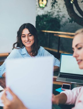 Bulanık bir bayan, terasta masada otururken ve serbest proje üzerinde çalışırken meslektaşlarına bilgilerle birlikte gülümsüyor ve kağıtları gösteriyor.