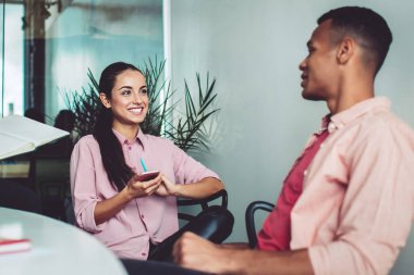 Başarılı çok kültürlü meslektaşlar, proje detayları hakkında brifing vermek için ofis içi içişlerinde zaman geçiriyorlar, pozitif erkek ve kadın girişimciler işbirliğinden keyif alıyorlar.