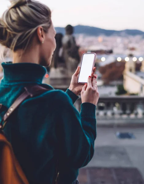 Back view of millennial woman with blank smartphone watching video guide during time for exploring Spanish capital - Barcelona using roaming internet for networking, female generation tracking gps