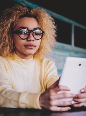 Gözlüklü çekici koyu tenli hippi kadın dijital dokunmatik ped üzerinden internet bağlantısı yoluyla sosyal ağda göz koruma profili güncellemesi sağlıyor, yeni nesil video izleyen kadın.