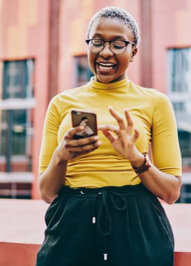 Mutlu Afro-Amerikalı kadın cep telefonuyla internet mağazasında satıştan heyecan duyuyor, neşeli esmer tenli hippi kız şehrin arka planında durmuş içeriğiyle gülüyor.