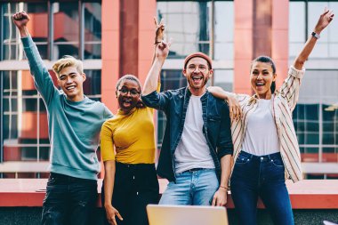 Sıradan giyinmiş neşeli hippilerin portresi dışarıda el ele tutuşurken kameraya gülümsüyor. Projenin tamamlanmasını kutlayan pozitif genç çok kültürlü insanlar.