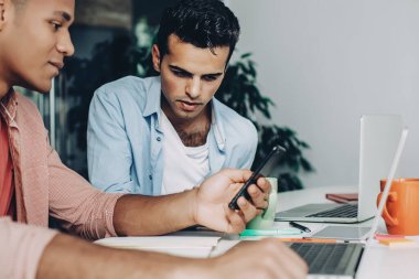 Akıllı telefon aygıtıyla online video izleyen çeşitli erkek çalışanlar masaüstünde bilgisayarlarla oturuyor, birlikte haberleşmenin keyfini çıkaran zeki meslektaşlar web sitesinde 4G 'ye bağlı haberleri okuyorlar.