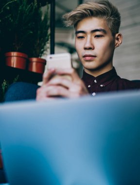 İletişim için akıllı telefonlarda yüksek hızlı internet bağlantısını kullanan yeni nesil milenyum. Çinli hipster blogcu cep telefonuyla sohbet ediyor. Laptop bilgisayarında birlikte çalışıyor.