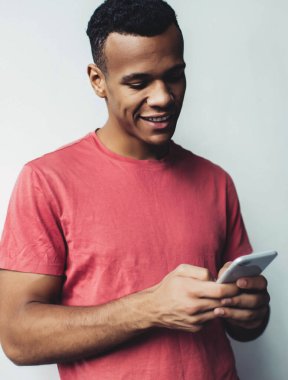 Mutlu koyu tenli adam cep telefonuyla online oyunlar oynuyor başarılı hipster adam tanıtım alanında arkadaşlarıyla mesajlaşırken akıllı telefondan e-postaları kontrol ediyor.