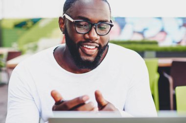 Başarılı esmer tenli hippi, video konferans sırasında internet kamerasıyla sohbet ederken en iyi arkadaşının sokak kafeteryasında internet bağlantısı var. Teknoloji kavramı.