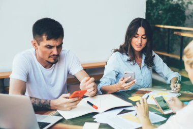 Proje hakkında brifing sırasında telefonlarda sörf yapan ve terastaki belgelerle masada buluşurken fikir arayan genç işçilerle ciddi etkileşimler.