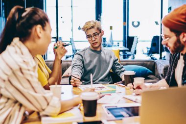 Erkek ve kadın çalışanlardan oluşan bir grup yetenekli erkek editörle toplantı masasında planlar hakkında konuşuyorlar, zeki kuşak çok ırklı mürettebat işbirliği yapıyor ve fikirler hakkında konuşuyorlar.