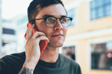 Gözlüklü genç adam görüş düzeltmesi için çevrimiçi müşteri hizmetlerini arıyor cep telefonunda gezinti bağlantısı için danışmanlık yapıyor, genç adam uygulamayla konuşmak için zaman harcıyor.