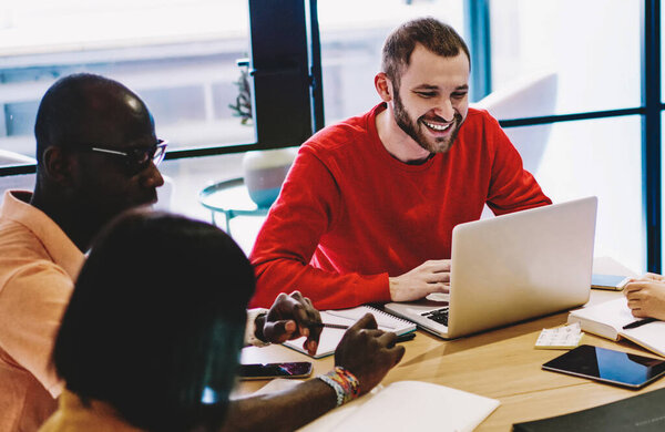 Smiling multiracial colleagues having meeting with couch enjoying friendly atmosphere for cooperation, prosperous team leader satisfied with productive cooperation with employees having fun and work