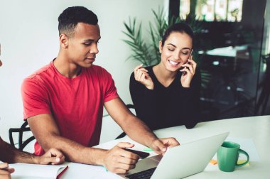 Çok ırklı iş arkadaşlarıyla yapılan beyin fırtınası sırasında internetteki web sitesi linki ile gündelik kıyafetlerle arama yapan Afrikalı Amerikalı erkek çalışanlar, başarılı bir cep telefonu araması yapan kadın.