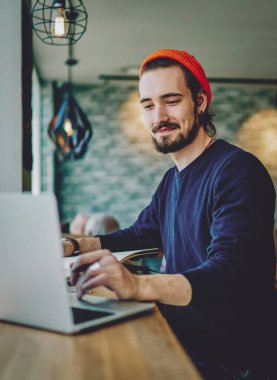 Reklam alanında uzaktan çalışan beyaz erkek haberleri kontrol ediyor. İnternet sayfasından bilgi okuyan serbest çalışan bir adam internete bağlı dizüstü bilgisayarın ekranına bakıyor.