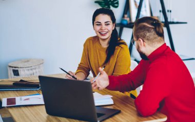 Neşeli yeniyetme kız, erkek arkadaşına bakıyor ve masaüstünde fikirleri tartışıyor, mutlu erkek ve kadın meslektaşlar sınavlara hazırlanırken sohbet ediyorlar.
