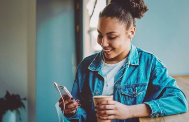 Neşeli bayan meloman grup sohbetinde arkadaşlarıyla sohbet ederken kendini iyi hissediyor. Müzik dinlemek için akıllı telefon uygulaması kullanıyor, cep telefonuyla gülümseyen hippi kız mesajlaşıyor.