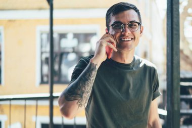 Gözlüklü mutlu hippi adamın yarım boy portresi akıllı telefon cihazında iyi gezinme bağlantısını kullanarak nesiller boyu dostça sohbet kavramını kullanıyor.