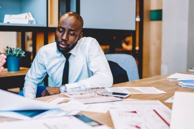 Afrikalı Amerikan CEO 'su ve Kafkasyalı girişimci resmi giyinmiş ortak projenin geliştirilmesi için iş stratejisini tartışıyorlar. İki finans müdürü çalışma planı hakkında konuşuyor.