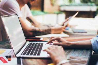 Terasta partnerle çalışırken boş ekranla dizüstü bilgisayara bakan yüzü olmayan bir kadının yan görünümü