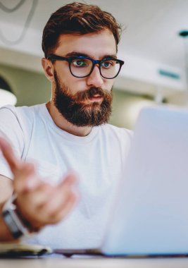 Genç bir erkek, vizyon koruması için gözlük takıyor. Bilgisayarında antivirüs programı var diye endişeleniyor. Kafkasyalı hippi el kol hareketi yapıyor.