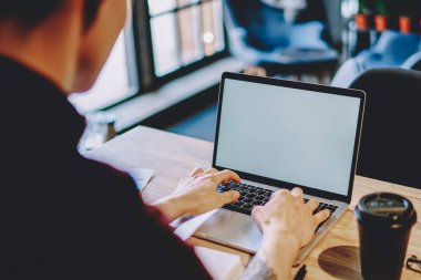 İnternet içeriğiniz için boş ekran alanı olan modern dizüstü bilgisayarın klavyesinde yazı yazan hipster öğrencilerinin arka planı. Genç adam ders için internet sayfası üzerinde ders çalışması yapıyor.