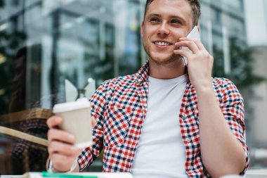 Ekose gömlekli, yakışıklı, sıradan bir adamın kahve içip caddede oturarak telefonda konuşmasından.