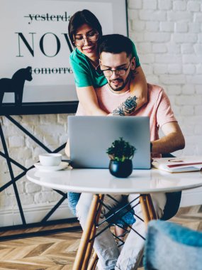 Mutlu eş, dizüstü bilgisayarla uzaktan eşine sarılıyor. Rahat bir dairede, şık bir şekilde çalışıyor. Olumlu kız arkadaş ve erkek arkadaş, modern netbook üzerinden video izliyor.