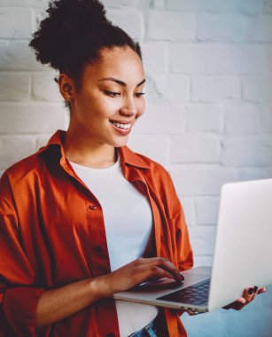 Koyu tenli hippi kız, modern dizüstü bilgisayarda kablosuz internete bağlıyken kendini iyi hisseden bir e-posta aldı. İndirme için film arayan ve boş zamanlarında izleyerek gülümseyen Afrikalı kadın.