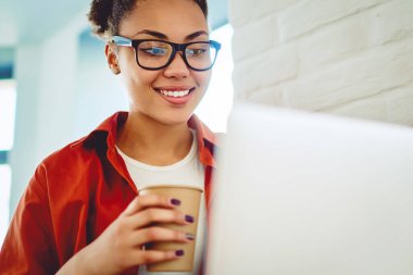 Üniversite kafeteryasında kahve molası sırasında çevrimiçi dil dersleri hakkında bilgi arayan mutlu kız öğrenci, netbook üzerinden komik videolar izleyen Afrikalı blogcu