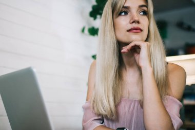 Genç, düşünceli, sarışın bir kadın. Çenesine eğilip, kafeteryada oturmuş dizüstü bilgisayarla çalışırken gözlerini kaçırıyor.